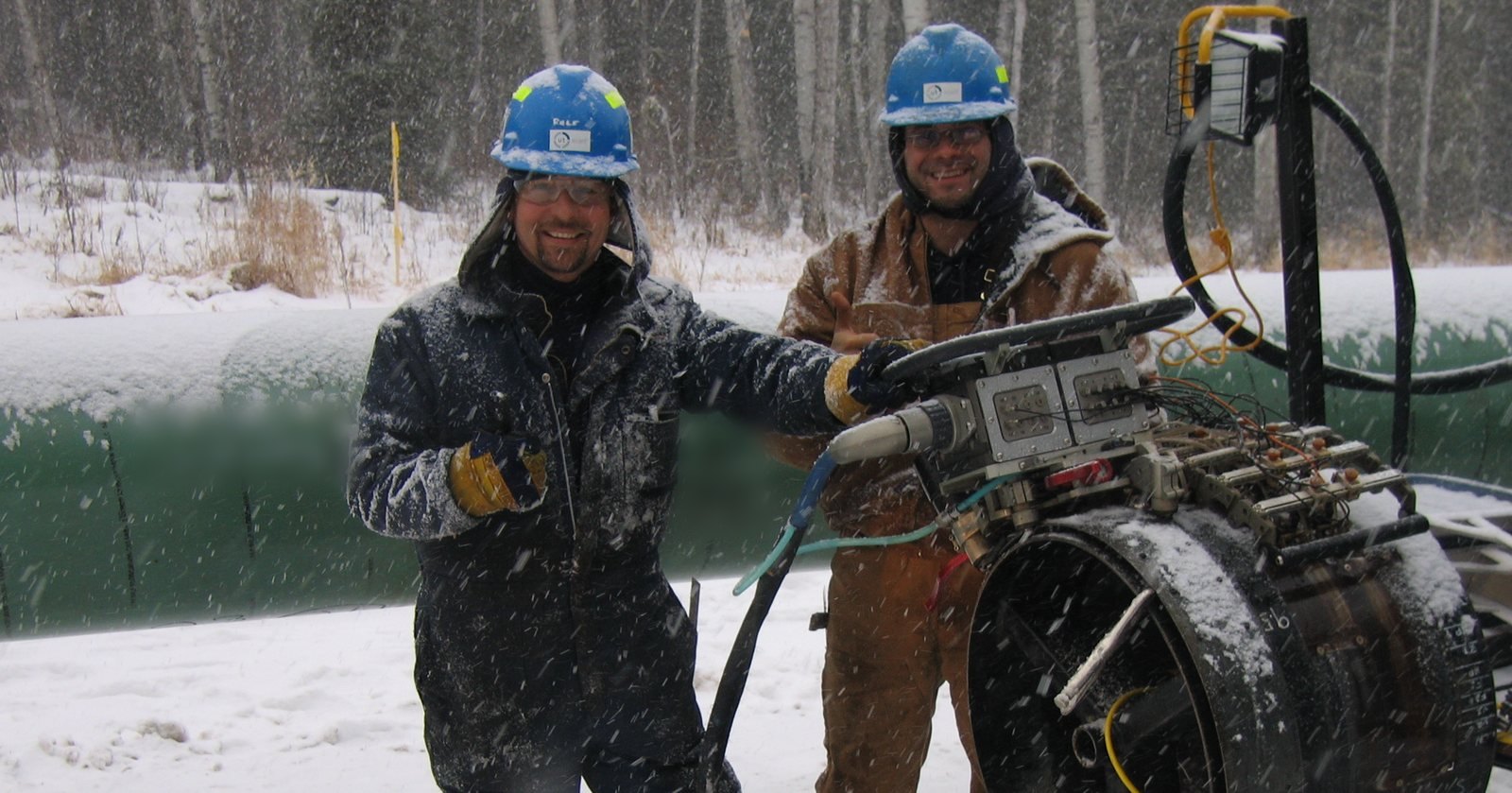 UT Quality technicians running an automated ultrasonic scanner on a pipeline girth weld in winter conditions