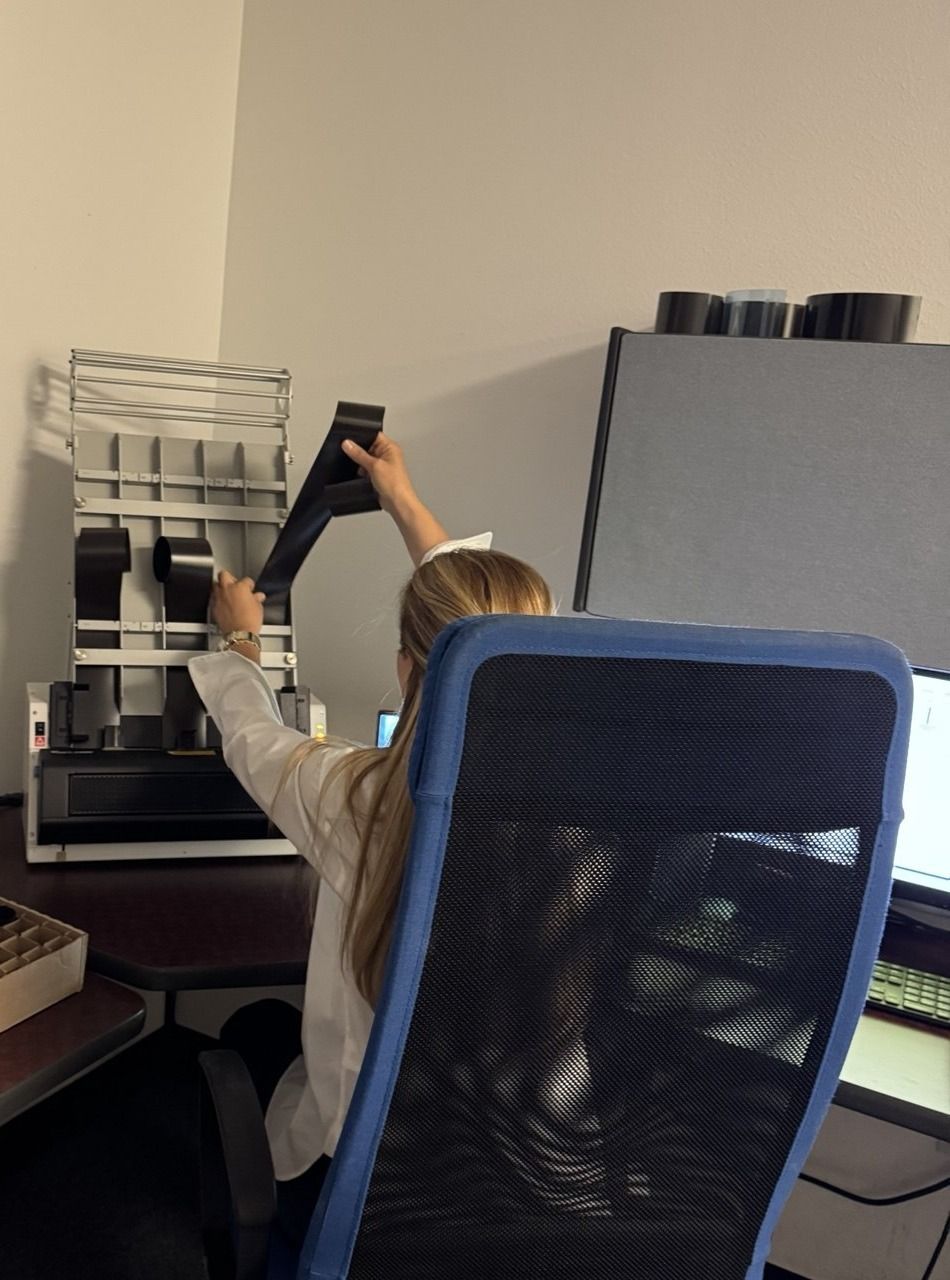 Technician feeding radiographic weld film into a film digitizer