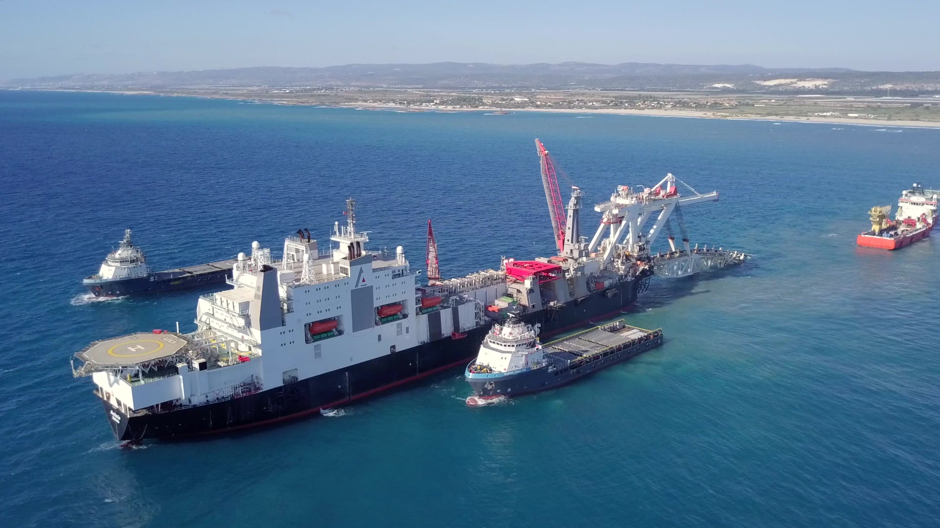 Aerial view of an offshore pipelay vessel with harbor tugs alongside, offshore pipeline construction