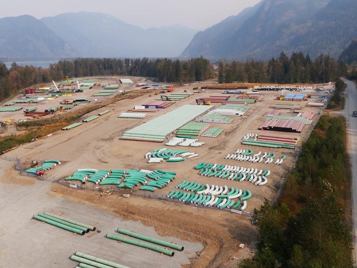 Aerial view of a coated-pipe laydown yard staged in a mountain valley