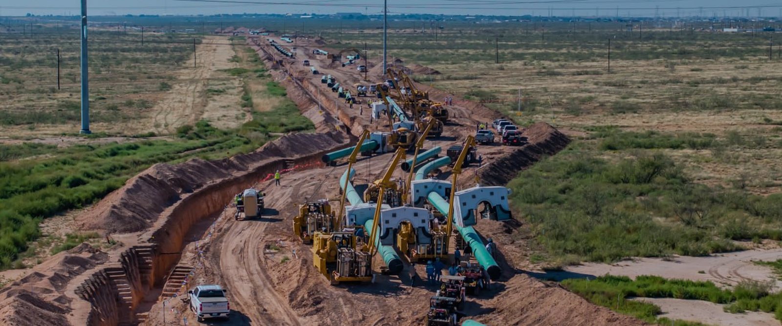 Pipeline right-of-way under construction with sideboom tractors and welding equipment working along the ditch