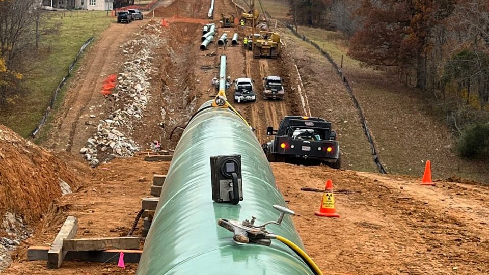 Aerial view down a pipeline right-of-way with a girth weld on the line in the foreground