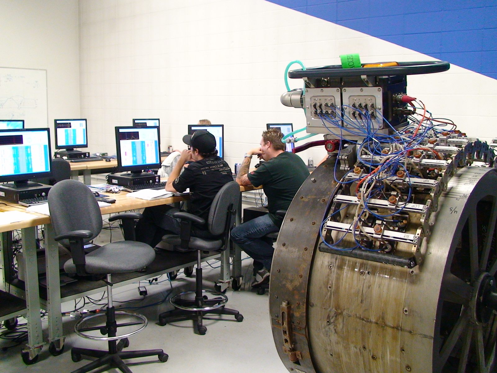 UT Quality technicians reviewing inspection data at workstations beside an automated ultrasonic scanner ring