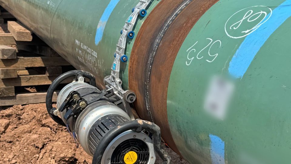 UT Quality USA technician with ultrasonic scanning equipment beside a pipeline and inspection truck