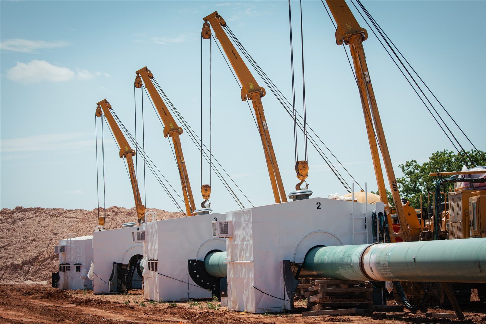 Row of pipeline welding shelters on sidebooms along a right-of-way