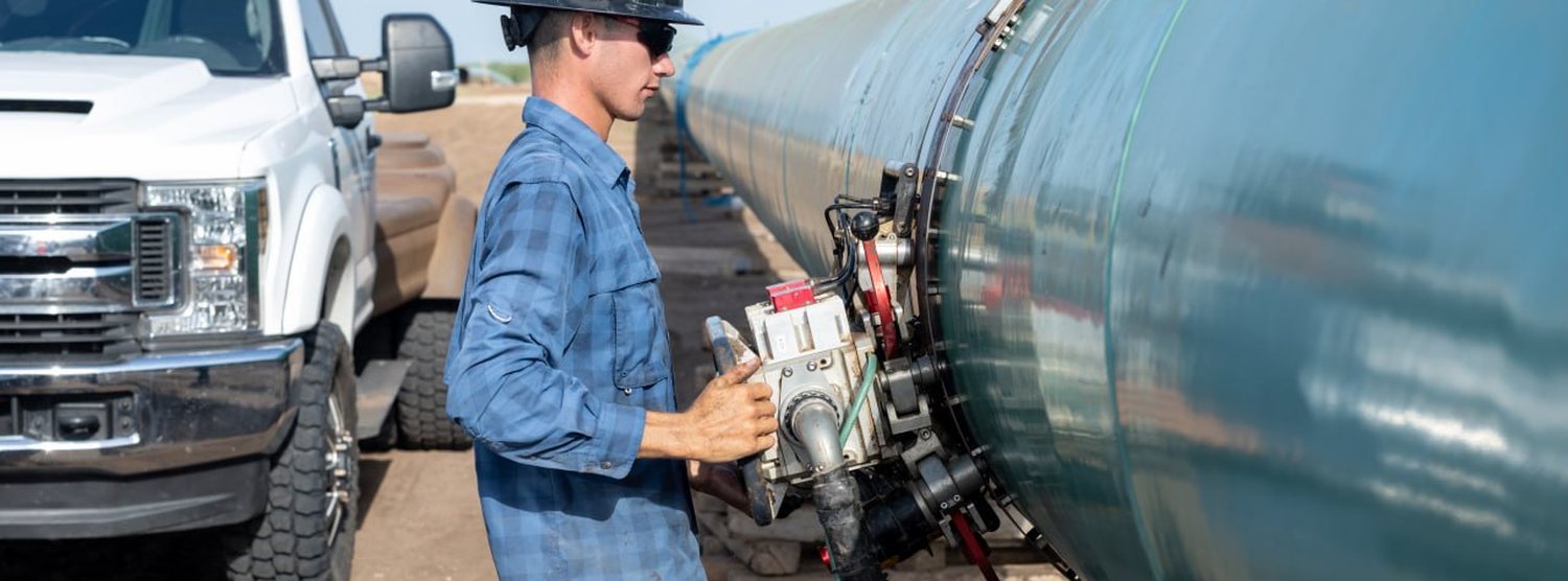 Technician running an encoded ultrasonic scanner around a large-diameter pipeline girth weld